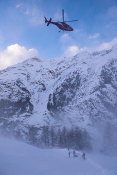 rescue team with a red helicopter rescuing a hurt skier