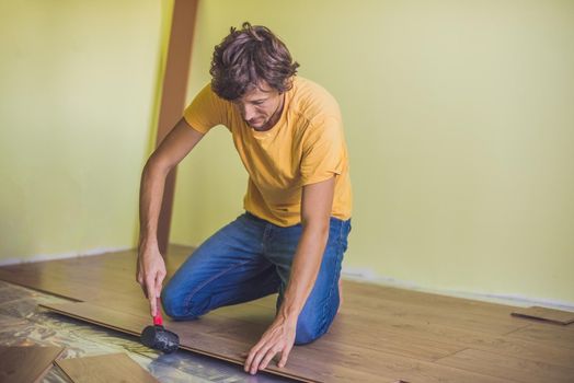 Man installing new wooden laminate flooring. infrared floor heating system under laminate floor