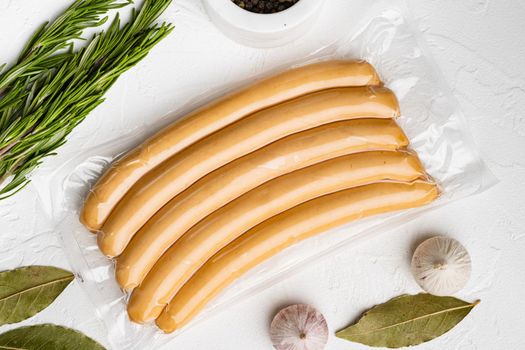 Sausages vacuum packed, on white stone table background, top view flat lay