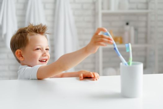 Little boy reaching out for toothbrush in bathroom
