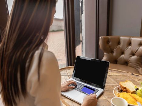 Woman working on laptop and holding credit card in coffee shop