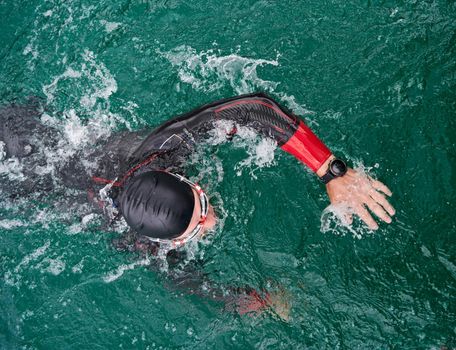 triathlon athlete swimming on lake wearing wetsuit