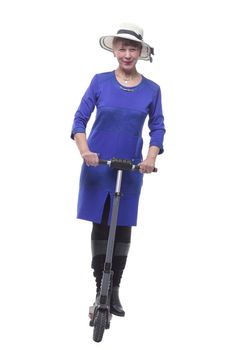 Pretty blonde woman in dress and hat riding a kick scooter