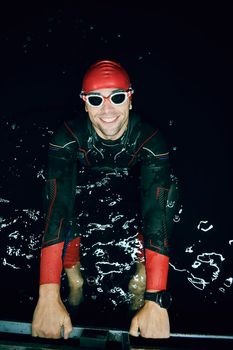 authentic triathlete swimmer having a break during hard training on night