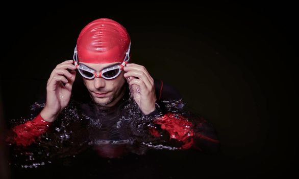 authentic triathlete swimmer having a break during hard training on night