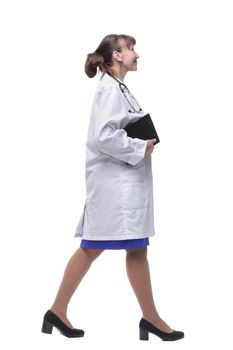 Beautiful woman in white coat carrying clipboard in one hand and walking