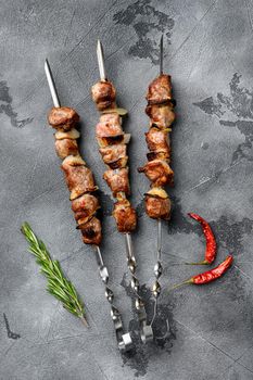 Juicy skewers of pork meat or shashlik, on gray stone table background, top view flat lay