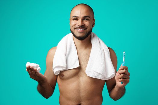 Mixed-race man with towel against turquoise background