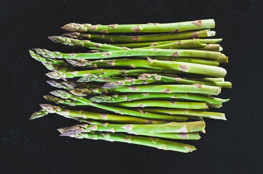 Green asparagus on a black background to restore the muscles of athletes and for the diet of girls. Balanced diet.
