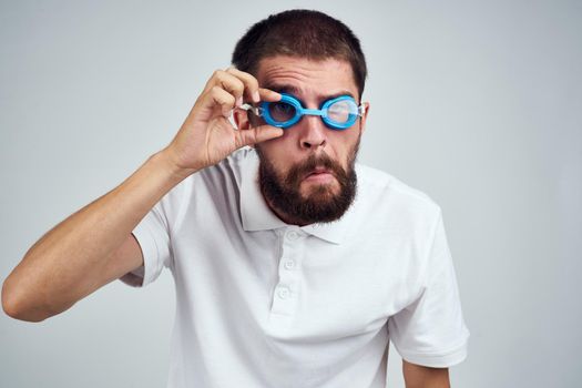 bearded man white shirt goggles for swimming light background