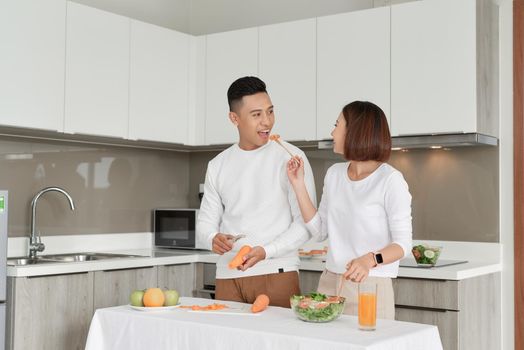 Happy couple standing in kitchen at home preparing together yummy dinner on first dating
