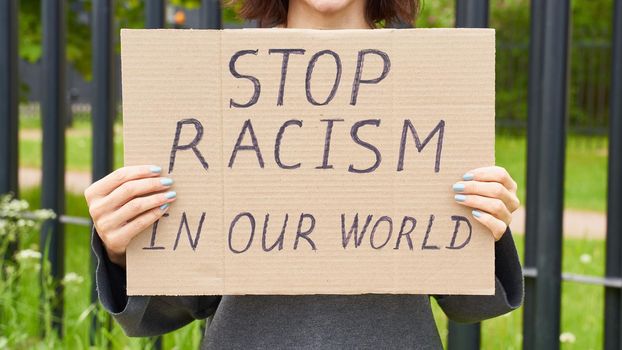 Stop racism concept. Unrecognizable white person holds sign with text against racist.