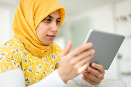 Muslim woman working on tablet at home