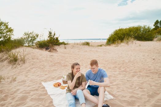 Picnic on beach with food and drinks. Young boy and girl sitting on sand