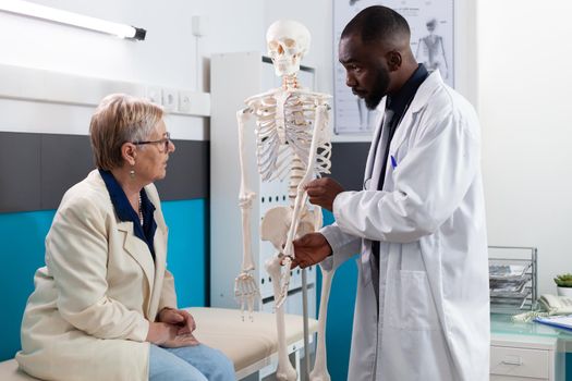 Specialist therapist doctor holding anatomical human skeleton arm explaining bones pain