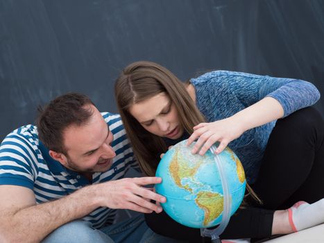 couple in casual clothing investigating globe