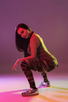 Attractive young brunette woman in the studio dancing Booty dance on a dark background