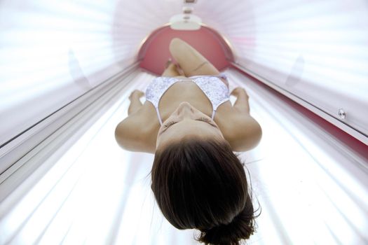 Beautiful young woman tanning in solarium