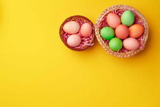Decorative nest with colorful Easter eggs on yellow background