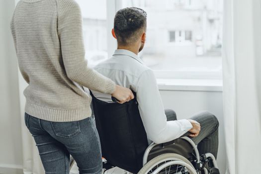Woman caring for disabled man in wheelchair at home
