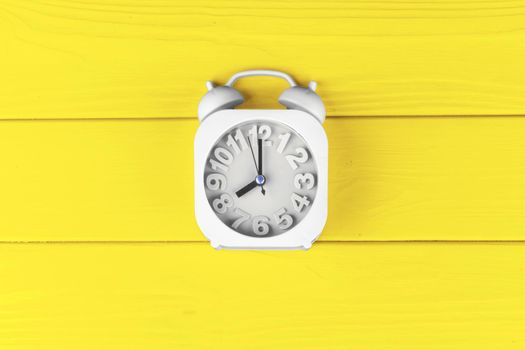 Top view of alarm clock on Illuminating Yellow background