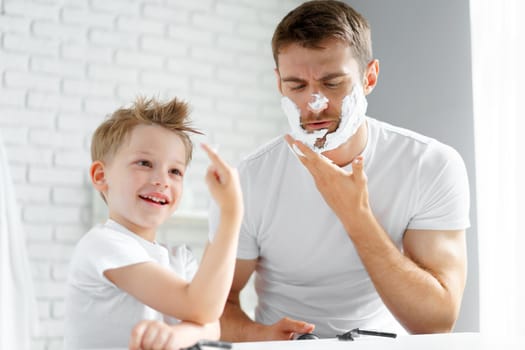Father teaches his little son how to shave face