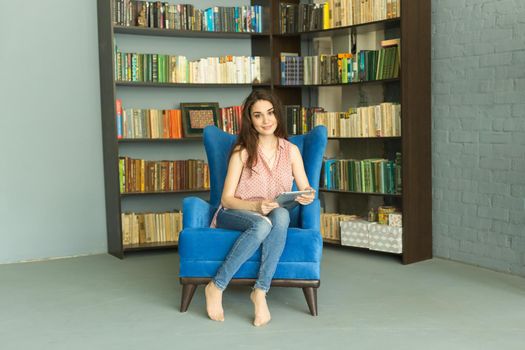 Leisure, people and home concept - Happy relaxed woman in home library