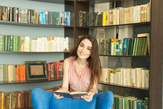 People, education and university concept - young student woman with a book in library