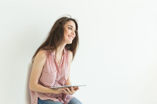 Technologies, emotions, people concept - young happy woman with tablet in her hands smiling over white background with copy space