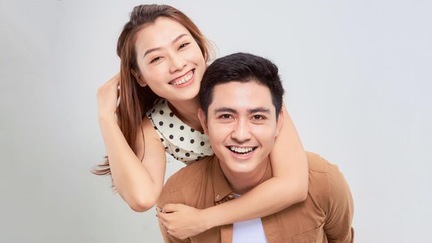 Man giving his pretty girlfriend a piggy back on white background