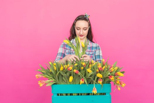 Brunette young woman with bunch of tulips on pink background