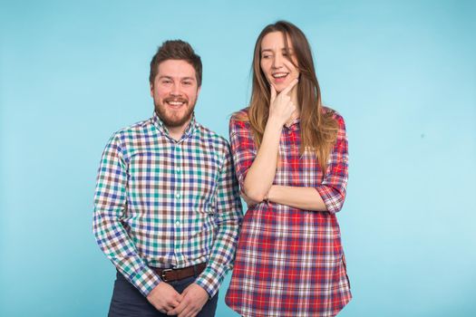 Portrait of cheerful laughing funny young lovers fooling around on blue background