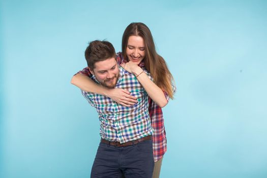 Portrait of cheerful laughing funny young lovers fooling around on blue background