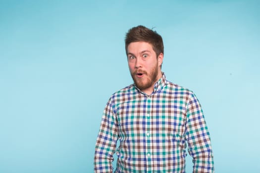 Close-up portrait of surprised bearded handsome man on blue background