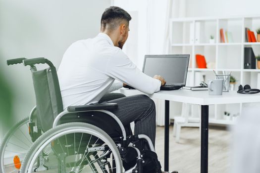 Disabled man in a wheelchair using laptop
