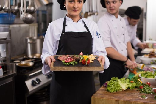 female Chef holding beef steak plate