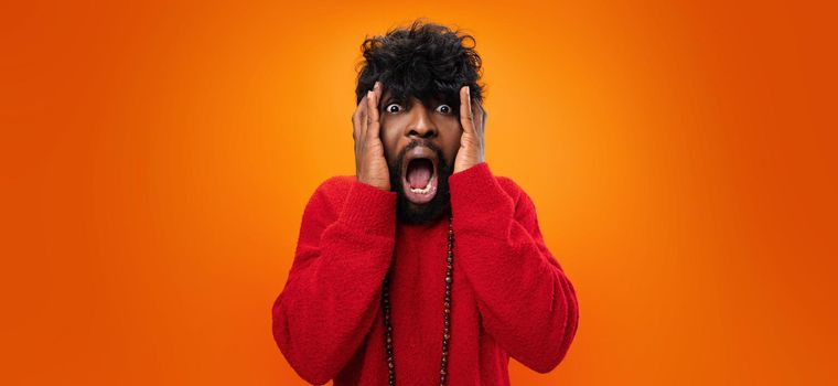 Young thrilled casual black man screaming on yellow background