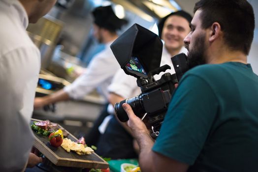 videographer recording while team cooks and chefs preparing meal
