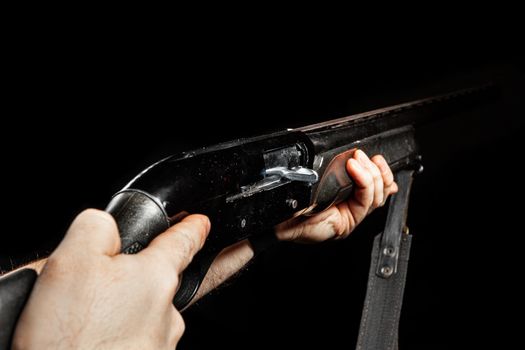 Male hands holding hunting rifle on black background