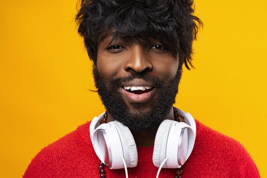 Young african american man with white headphones against yellow background