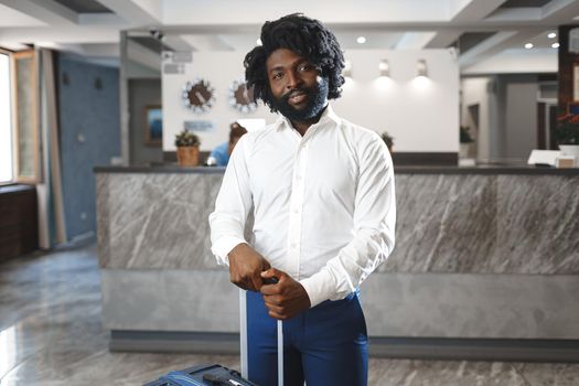 Black businessman with packed luggage standing in hotel lobby