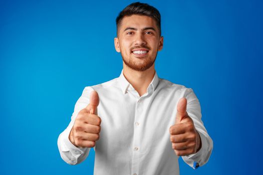 Positive handsome hispanic businessman showing thumb up gesture
