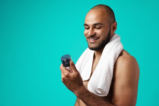 Happy african american man with towel holding shaving foam