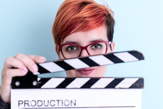 woman holding movie clapper against cyan background