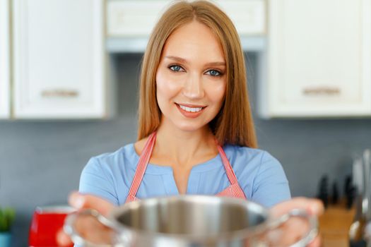Attractive young blonde woman checking cooked food