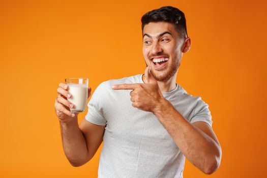 Happy smiling mixed-race man holding milk against yellow background