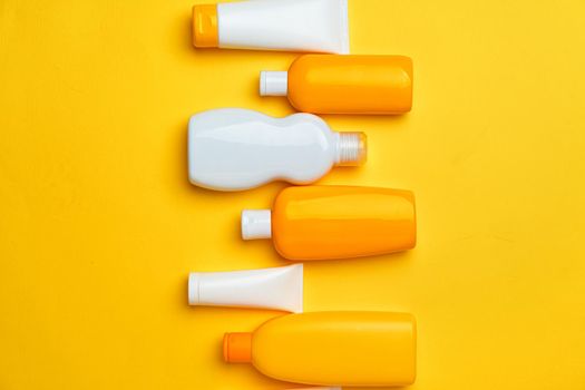 Collection of sunscreen cream bottles on yellow background
