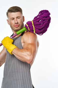 muscular man in a gray apron with a mop posing
