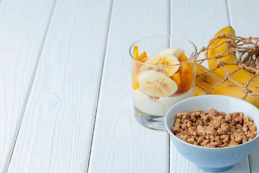 Tasty breakfast with granola, yoghurt and fruits in a glass bowl