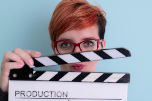 redhead woman holding movie  clapper on cyan background